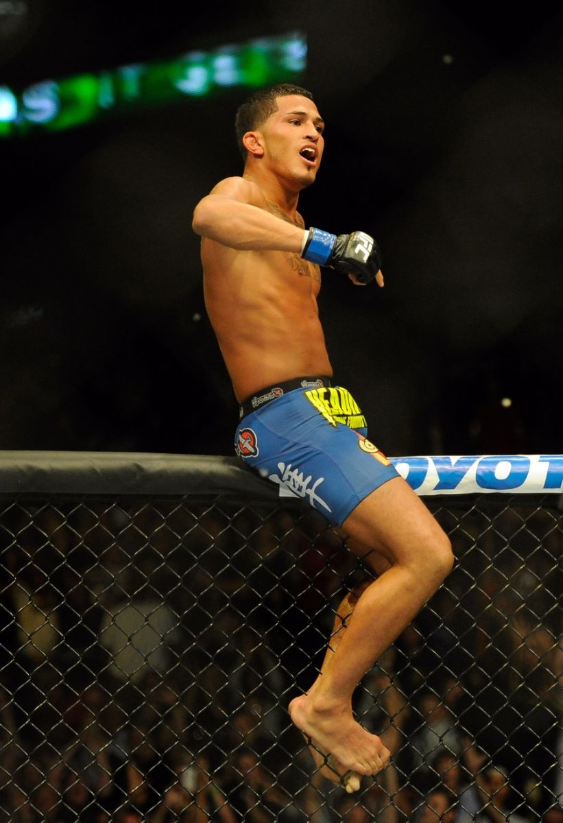 Anthony Pettis celebrates his UFC 164 victory over Benson Henderson on top of the cage