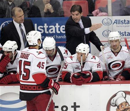 Carolina Hurricanes head coach Peter Laviolette talks to David Tanabe during a break in the third period of their NHL hockey game against the Detroit Red Wings at Joe Louis Arena in Detroit