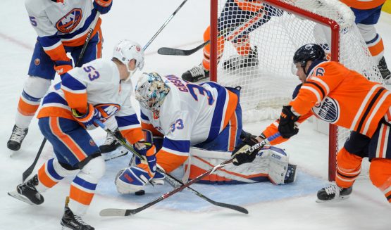 Mar 8, 2018; Edmonton, Alberta, CAN; New York Islanders goalie Christopher Gibson (33) battles for the puck with Islanders center Casey Cizikas (53) and Islanders defenceman Johnny Boychuck (55) helps as Edmonton Oilers right winger Iiro Pakarinen (26) skates towards them during the first period at Rogers Place. Mandatory Credit: Walter Tychnowicz-USA TODAY Sports