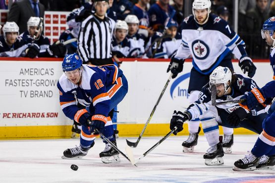 Dec 4, 2018; Brooklyn, NY, USA; New York Islanders right wing Josh Bailey (12) and Winnipeg Jets left wing Mathieu Perreault (85) reach for the puck during the third period at Barclays Center. Mandatory Credit: Dennis Schneidler-USA TODAY Sports