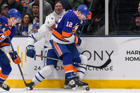 Apr 1, 2019; Uniondale, NY, USA; Toronto Maple Leafs center John Tavares (91) and New York Islanders right wing Josh Bailey (12) battle for the puck on the boards during the second period at Nassau Veterans Memorial Coliseum. Mandatory Credit: Dennis Schneidler-USA TODAY Sports