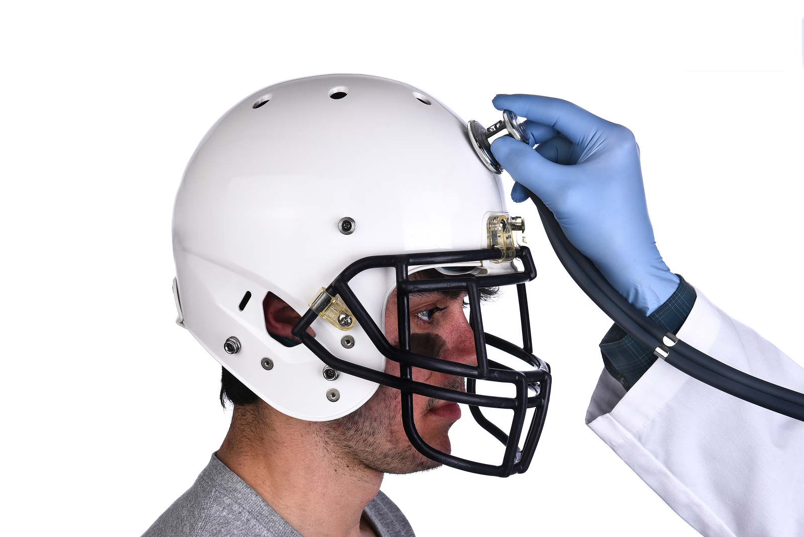 A football player wearing a helmet with doctors hand holding a s
