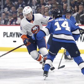 Oct 17, 2019; Winnipeg, Manitoba, CAN; New York Islanders right wing Oliver Wahlstrom (26) tries to control the puck from Winnipeg Jets defenseman Ville Heinola (14) in the first period at Bell MTS Place. Mandatory Credit: James Carey Lauder-USA TODAY Sports