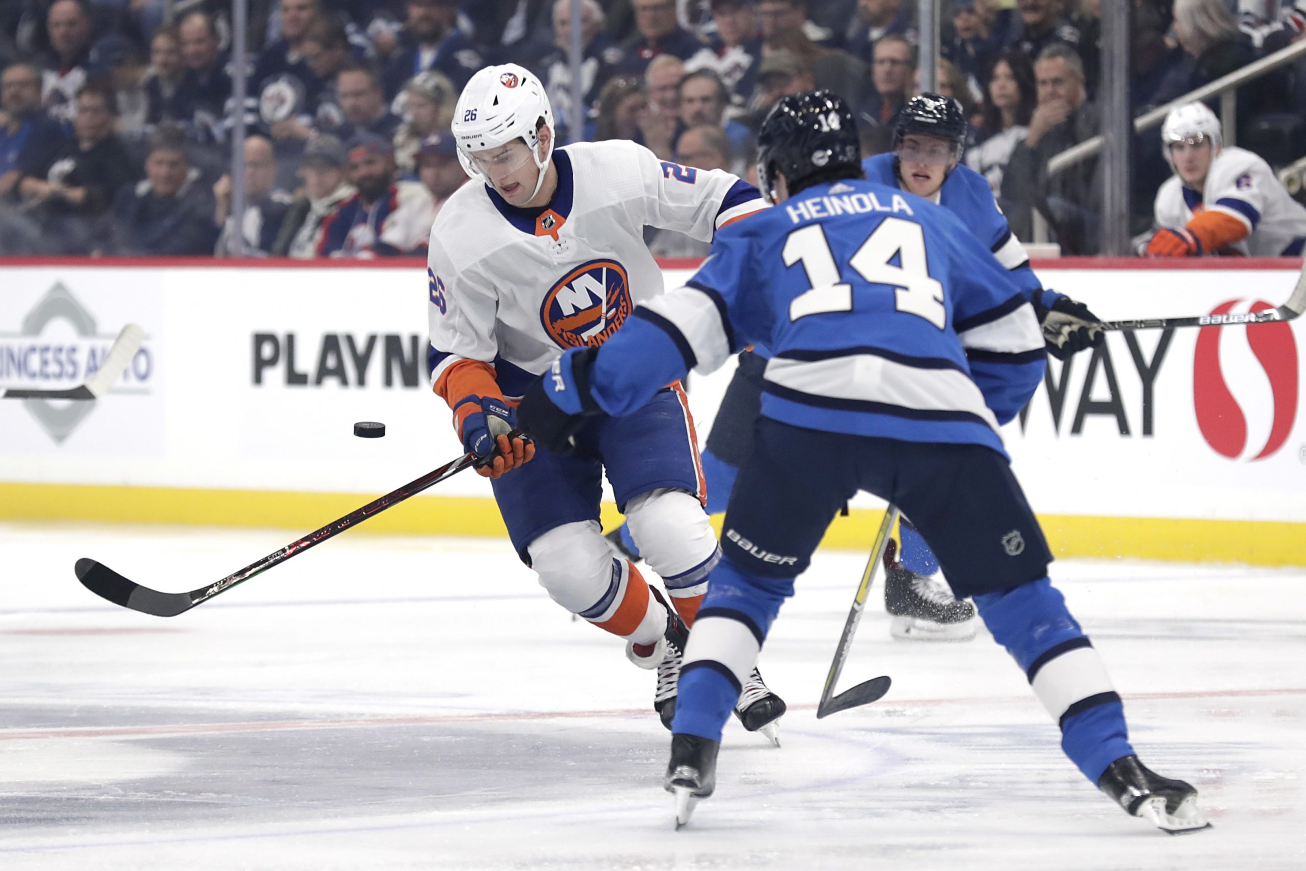 Oct 17, 2019; Winnipeg, Manitoba, CAN; New York Islanders right wing Oliver Wahlstrom (26) tries to control the puck from Winnipeg Jets defenseman Ville Heinola (14) in the first period at Bell MTS Place. Mandatory Credit: James Carey Lauder-USA TODAY Sports