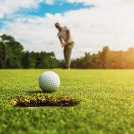 golf player putting golf ball into hole